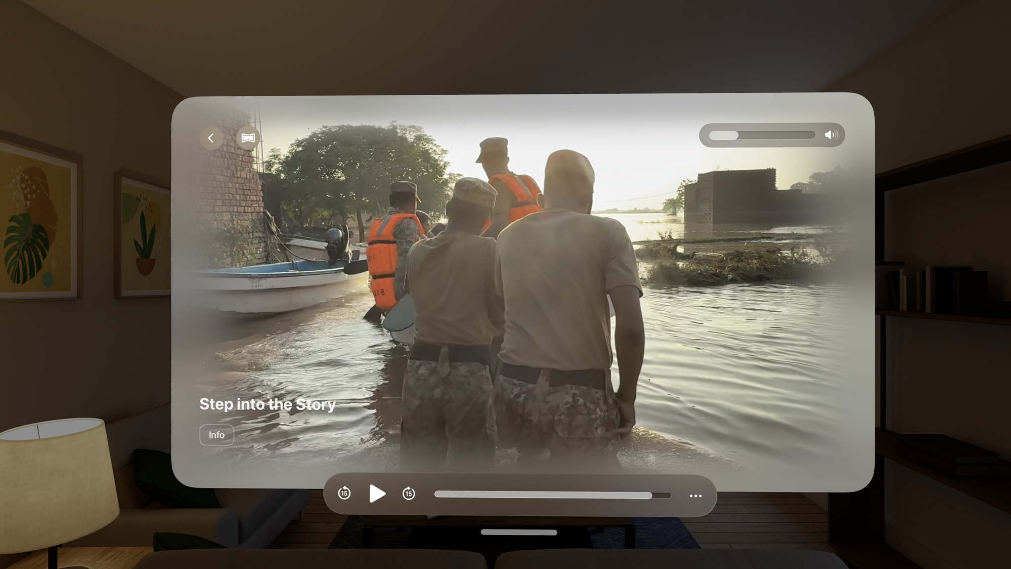 A screen from Primary is shown in a video player floating in a virtual living room. The video depicts rescue workers in orange life vests wading through floodwaters toward a boat at golden hour.