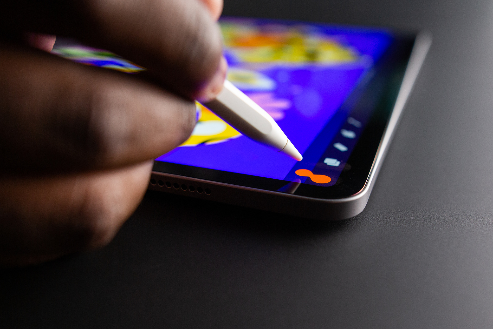 A photo of a person using Apple Pencil with Procreate’s ColorDrop feature to drag a color from the menu to the canvas.