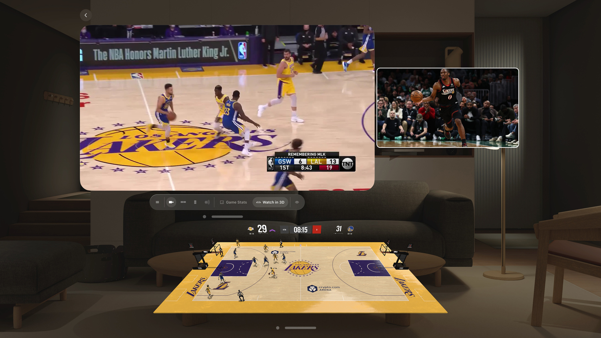 A large 3D virtual basketball court branded for the Los Angeles Lakers and Crypto.com Arena fills a virtual living room space in Apple Vision Pro, with animated player figures representing a live Lakers vs. Warriors game. Above the court, two video windows show the live broadcast and a second game in picture-in-picture, alongside a scoreboard showing the Lakers trailing 29–31 in the fourth quarter. the Lakers trailing 29–31 in the fourth quarter.
