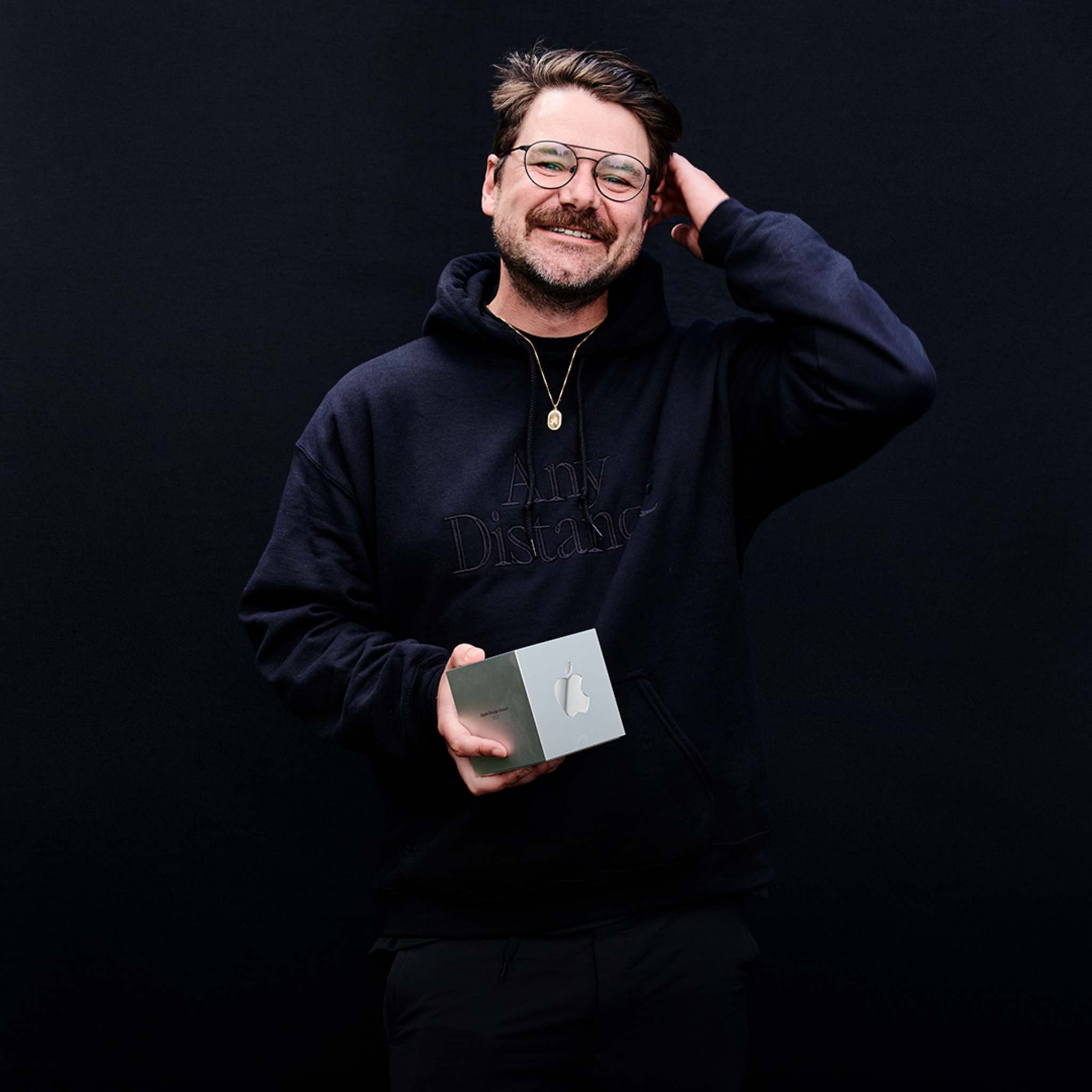 A portrait of Luke Beard, Any Distance founder, holding his Apple Design Award. 