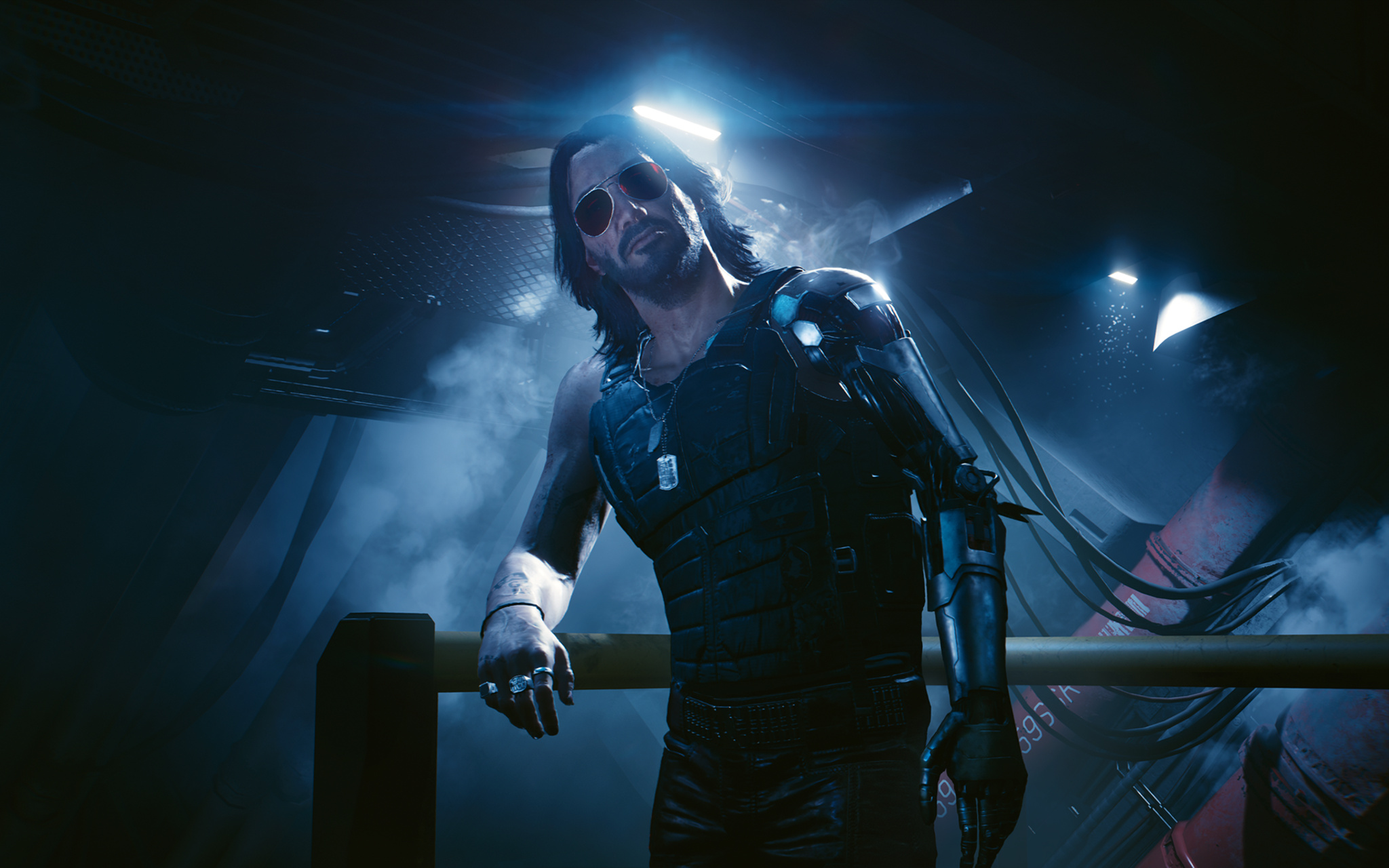 A dramatic low-angle shot from Cyberpunk 2077 of Johnny Silverhand — long dark hair, red-tinted aviator sunglasses, a gleaming cybernetic arm — leaning casually against a railing as haze drifts around him. He wears a black sleeveless vest and dog tags, and his expression is cool and confrontational. Harsh overhead lighting cuts through the smoke, casting hard shadows across his face and chrome arm..