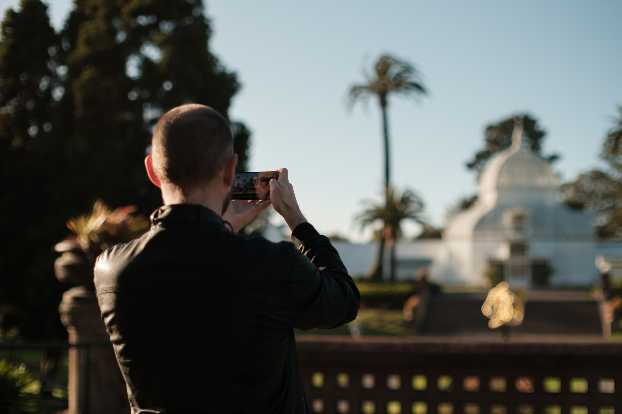 Lux Optics co-founder Ben Sandofsky stands on a porch taking a picture of a building. 